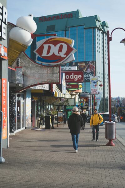 A lively street in Niagara Falls with pedestrians, iconic logos, and skyscrapers.