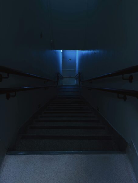 Dimly lit stairs in an indoor setting with eerie blue lighting creating a mysterious ambiance.