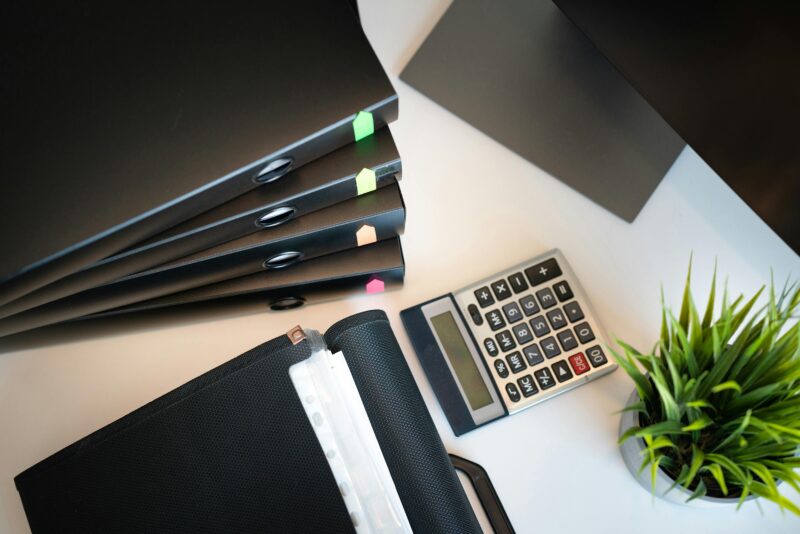 Top view of a tidy office desk with files, a calculator, and a plant, emphasizing organization.