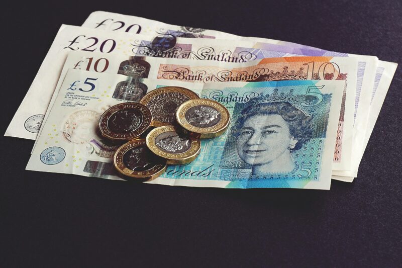 High-quality image of British pound notes and coins on a dark surface, showcasing currency detail.