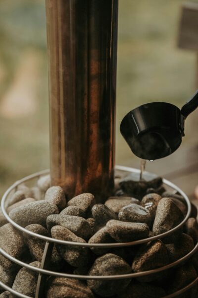 A sauna heater surrounded by stones with water being poured, creating a warm atmosphere.