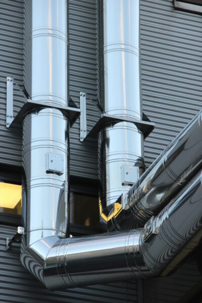 Close-up of shiny stainless steel pipes on an industrial building facade, showcasing modern technology.