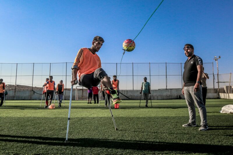 A group of amputee soccer players train with a ball on a sunny day in Syria.