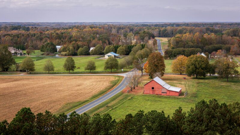 Aerial view of a picturesque farm landscape with fields and a red barn in fall.