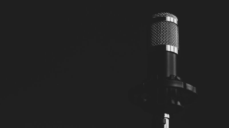 Close-up view of a studio microphone against a dark background, emphasizing audio technology.