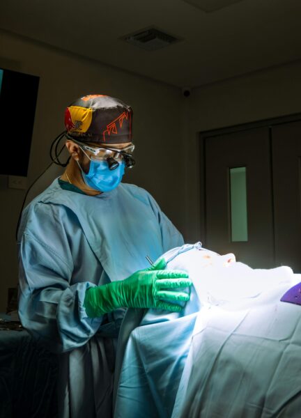 Surgeon in protective gear conducting a medical procedure in an operating room.