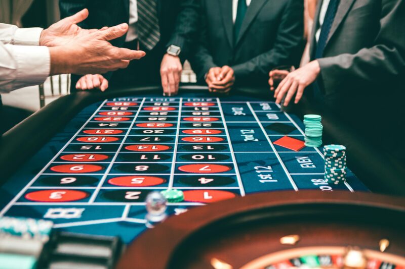 Group of people playing roulette in a casino setting.