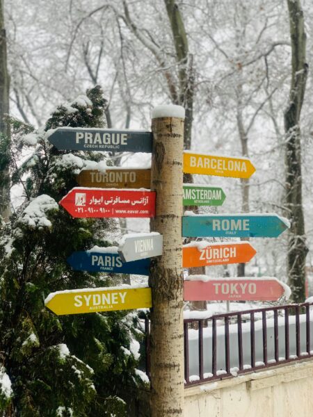 Colorful signpost displaying international city names against a snowy background.