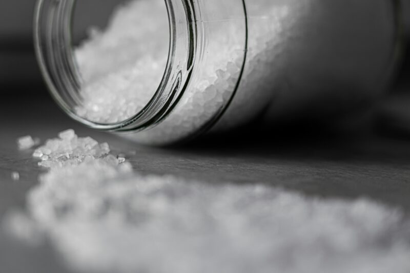 Detailed image of rock salt pouring out from a glass jar with a selective focus effect.