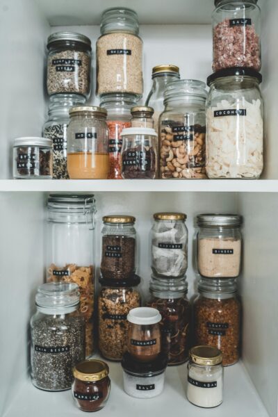 Well-organized pantry with eco-friendly reusable glass jars and labels for easy food storage.