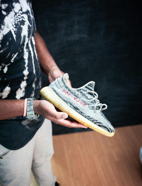 Close-up of a person holding Yeezy Boost sneakers indoors, showcasing fashion style.