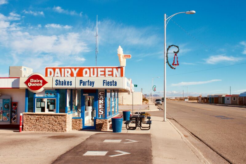 Exterior view of an iconic Dairy Queen under a clear blue sky, capturing a vintage vibe.