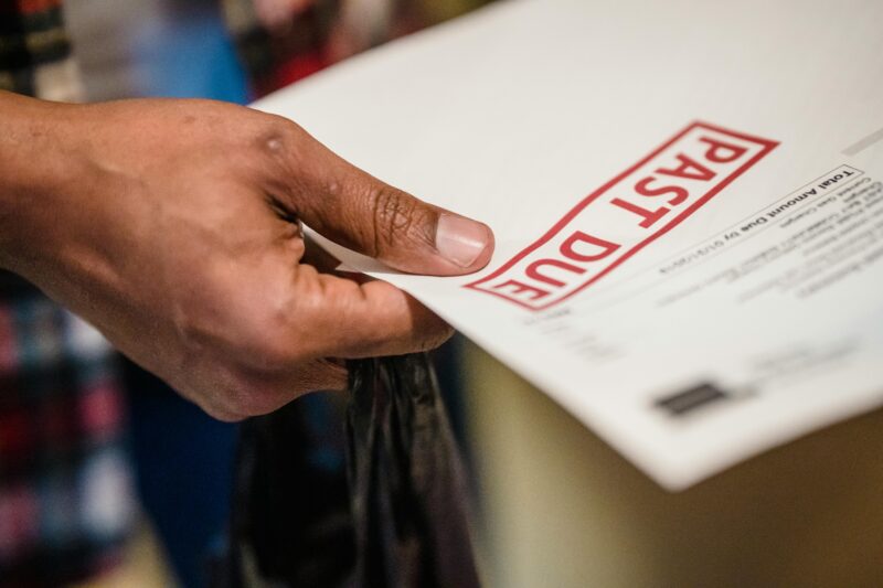 A close-up of a hand holding a document with a 'Past Due' stamp, highlighting financial urgency.