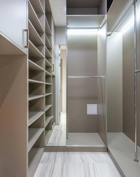 Minimalist walk-in closet with shelves, mirror, and ample storage space.