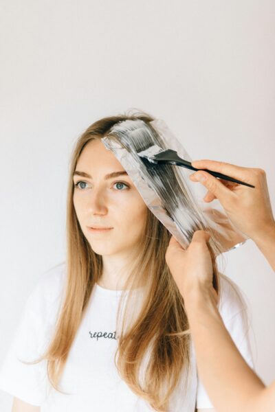 Woman getting blonde hair treatment in a salon with professional stylist applying dye.