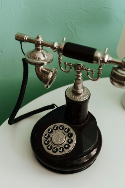 Close-up of a classic black rotary dial telephone on a white table, vintage style.