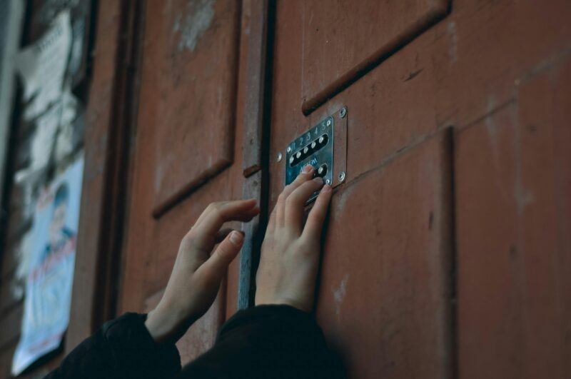 Close-up of hands pressing a keypad on a wooden door, showcasing security and access entry.