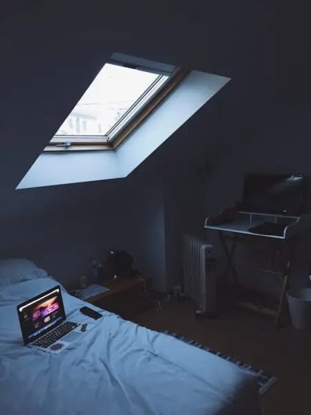 A modern home office setup in a cozy attic bedroom with skylight