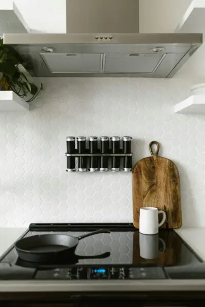 Contemporary kitchen featuring an induction stove, spice rack, and wooden chopping board.
