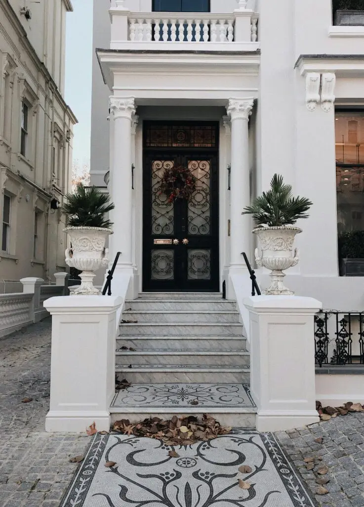 Wide-angle view of a classic luxury townhouse entrance in London featuring ornate columns and potted plants