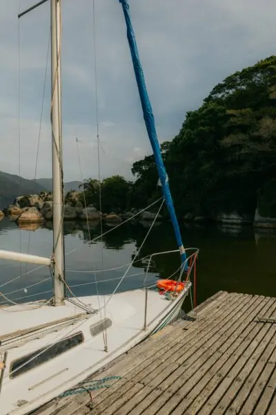 A tranquil sailboat at a wooden dock in Santa Catarina, Brazil, surrounded by lush greenery.