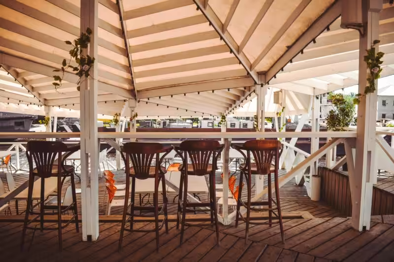 Elegant outdoor cafe with wooden furniture and decor, offering a cozy and stylish atmosphere.