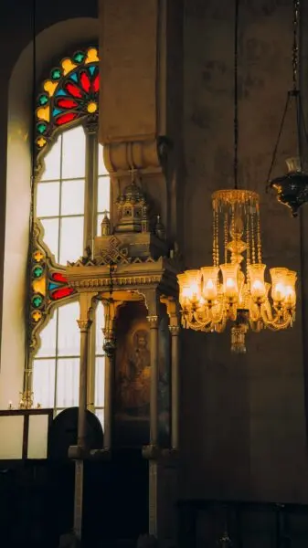A beautiful church interior featuring a stained glass window and a vintage chandelier.