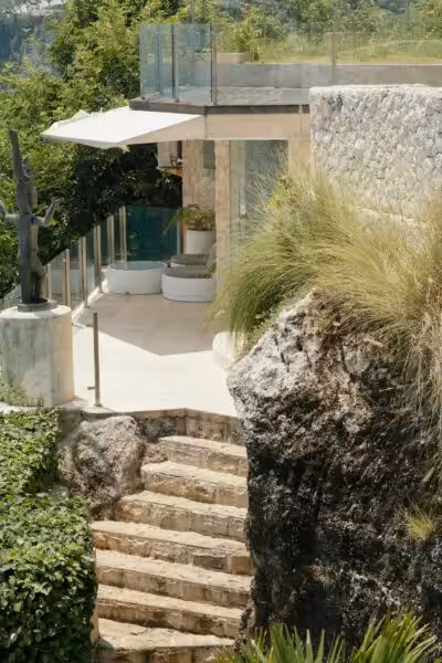 A luxurious terrace with stone steps, lush greenery, and a modern statue.