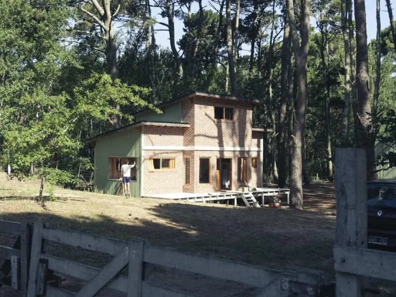 Brown wooden house near green trees during daytime.