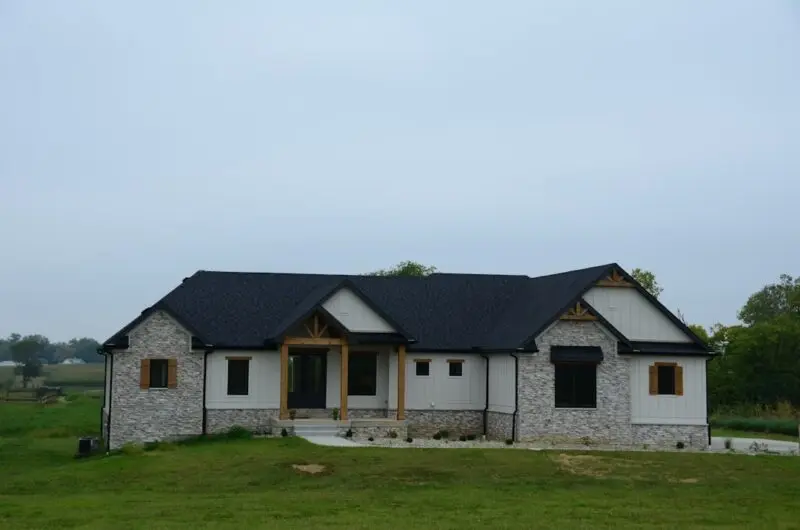 Stone house with black roof and windows.