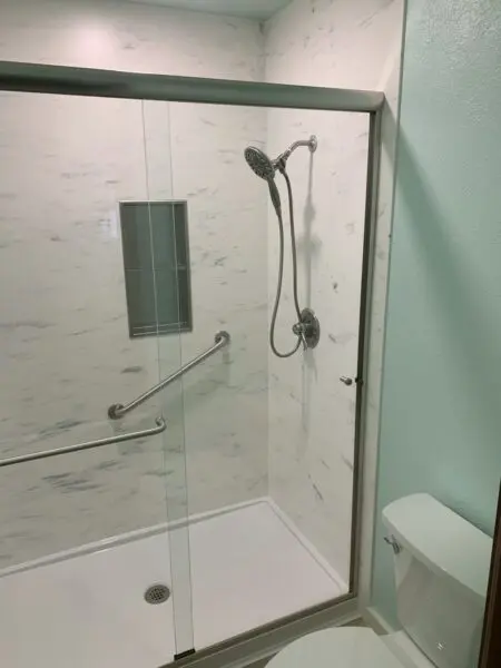 A bathroom with a glass shower door and a toilet.