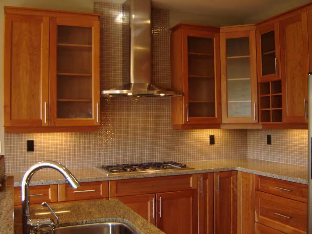 Patterned wallpaper protected by glass as a backsplash in a small apartment kitchen.