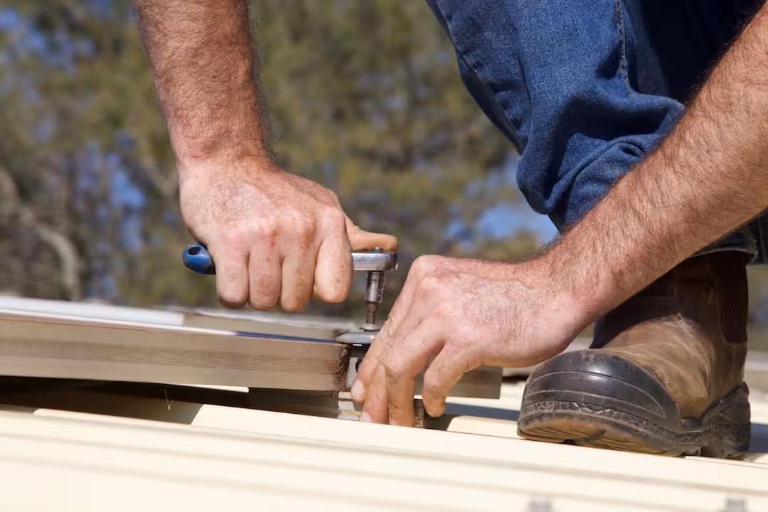 Hands using a tool to fasten metal roofing.