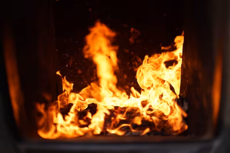 Bright flames in a dark furnace create a warm, vibrant atmosphere.