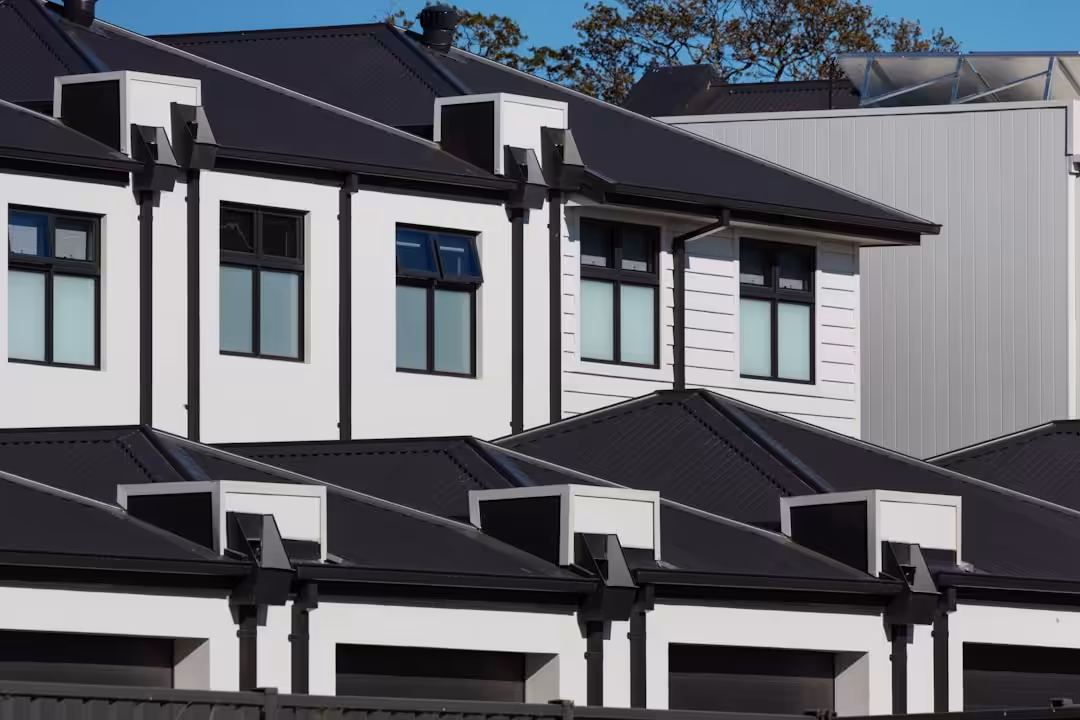 Row of modern white houses with black roofs