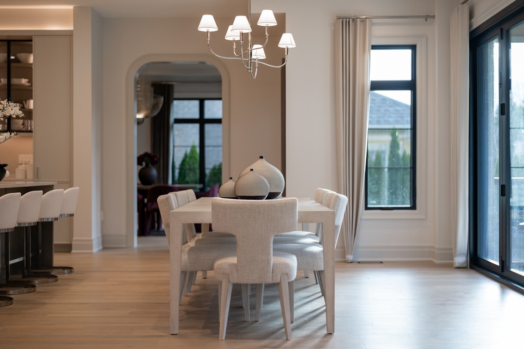 Elegant dining room with white table, chairs, and large windows.