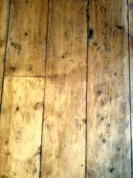 A weathered old wood floor with visible grain and knots, showing signs of wear.