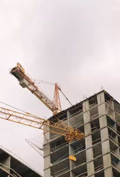 A high-rise building under construction with visible tower cranes and concrete structure.