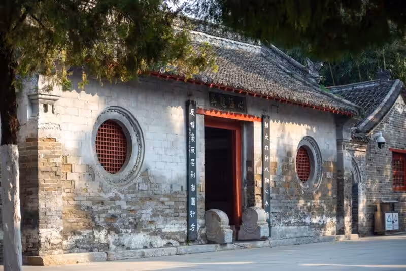 Ancient Chinese temple entrance showcasing traditional architecture with round windows and a tiled roof.