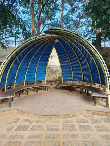 Bamboo canopy outdoor seating with benches in a serene natural setting.