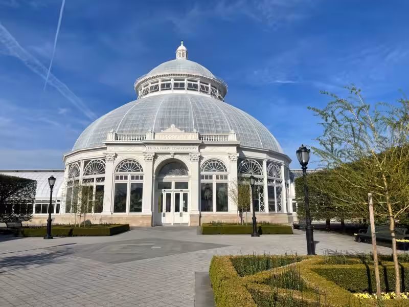 Front view of the Enid A. Haupt Conservatory on a sunny spring day at the New York Botanical Garden.