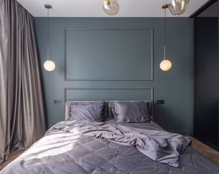 Interior design of modern bedroom with unmade bed under luminous lamps at sunlight