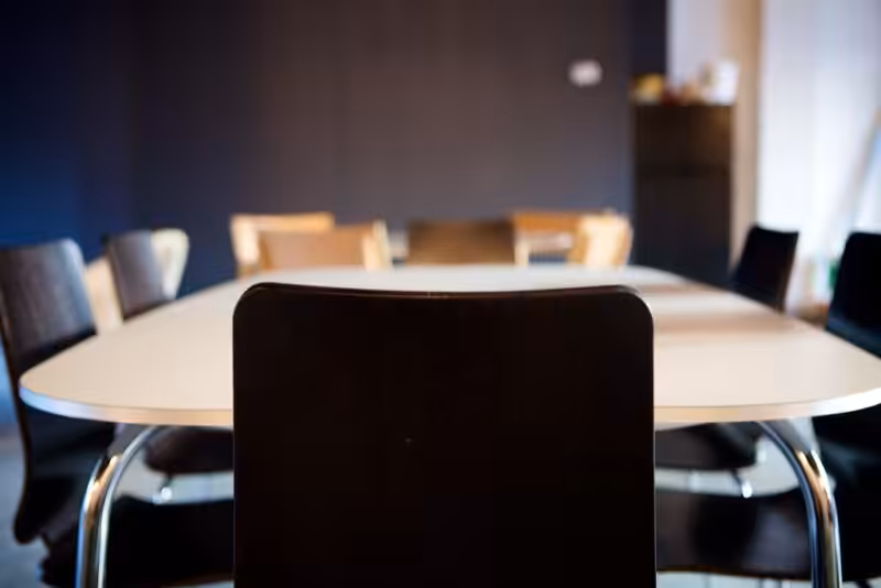 A minimalist conference room setting with a round table and modern chairs, suitable for business meetings.