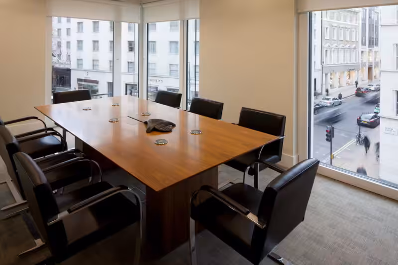 An elegant corporate meeting room featuring a long table and modern seating arrangements.