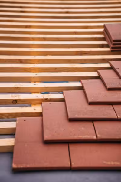 Red roofing tiles and wooden framework in progress on a building roof.