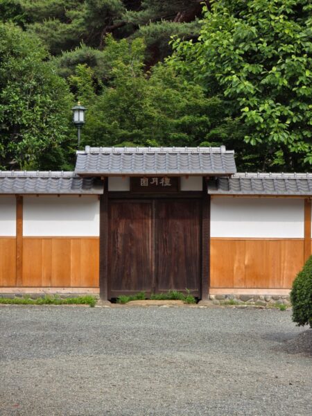 Serene Japanese garden entrance showcasing a classic wooden gate and lush greenery.