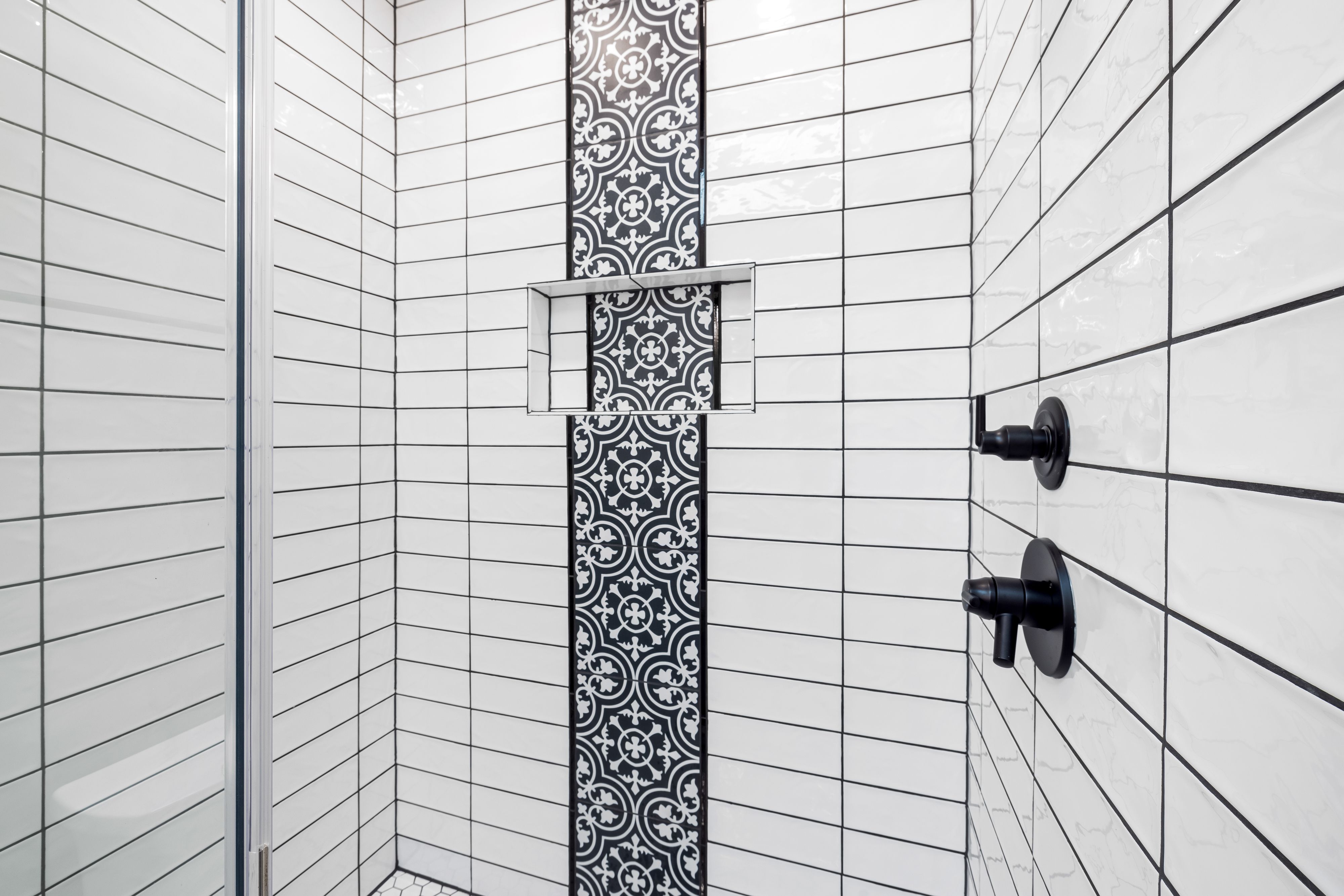 Stylish shower area featuring black and white geometric tiles and contemporary fixtures.