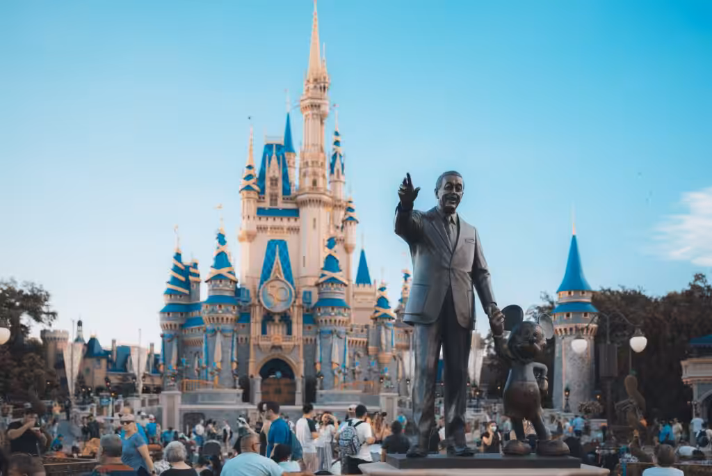 View of the iconic Cinderella Castle at Walt Disney World in Orlando, Florida, with crowd and statue.