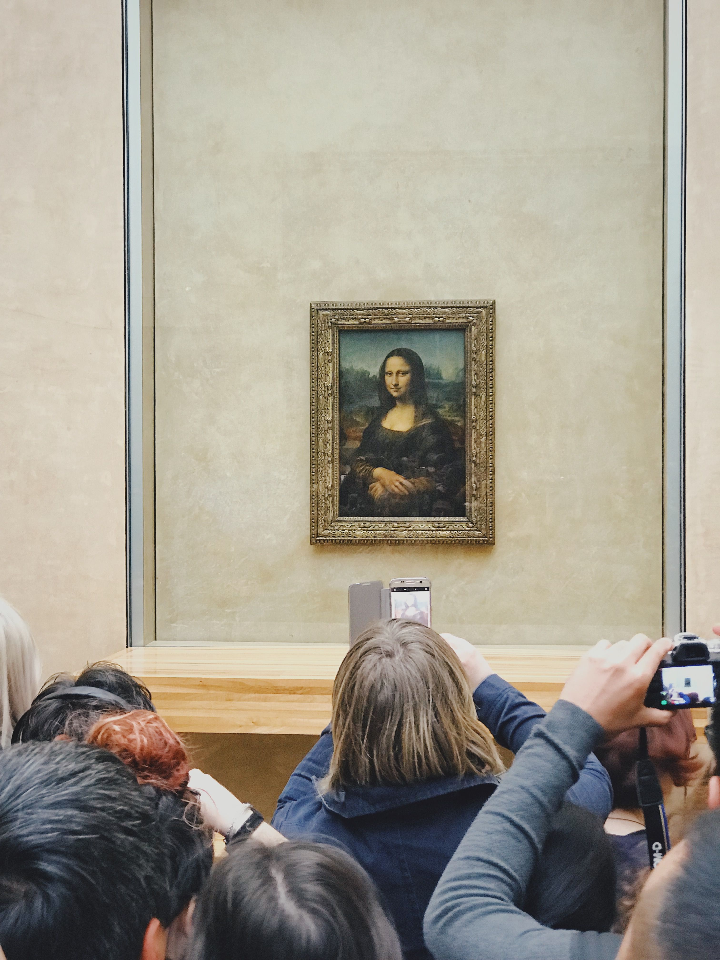 A crowd of visitors photographs the Mona Lisa at the Louvre Museum in Paris, France.