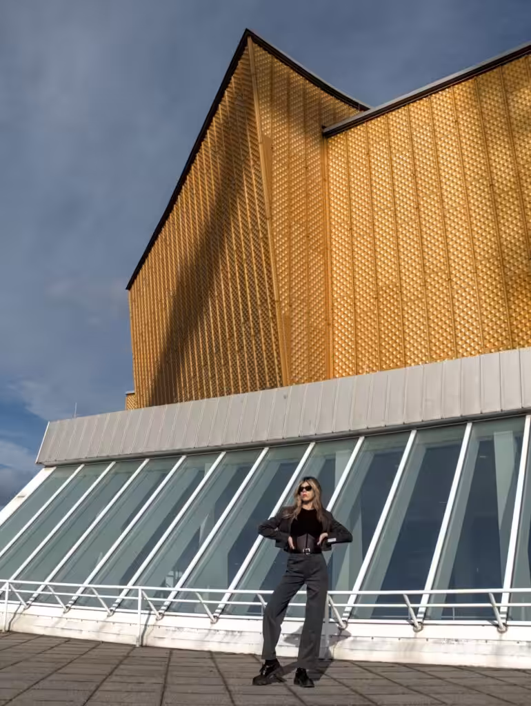Modern architecture with a woman posing outdoors under a vibrant yellow facade.